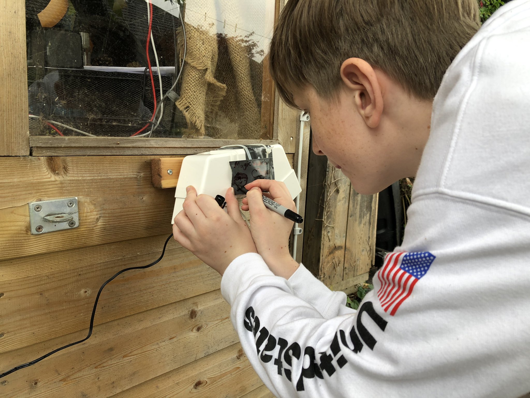 The boy attaching the monitor to the side of the shed