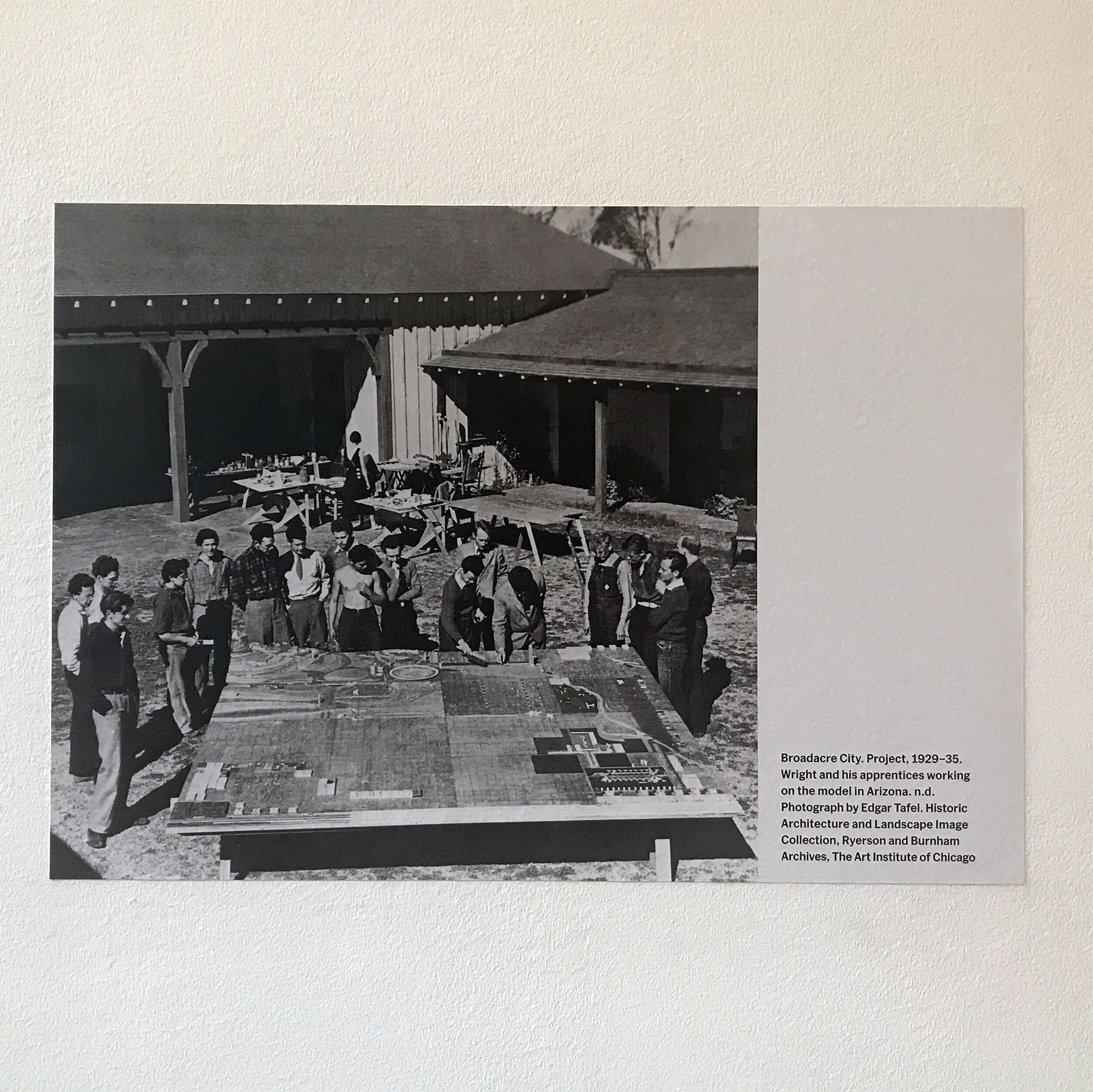 A shot of Wright and his apprentices looking over a model of Broadacre